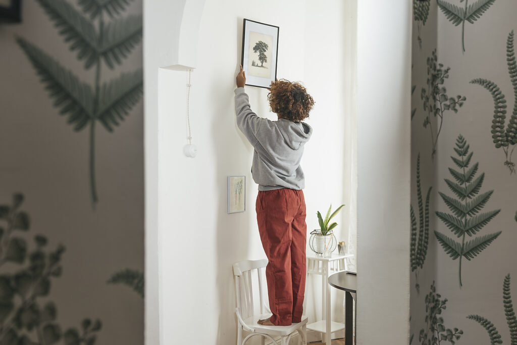 Woman hanging up picture at home